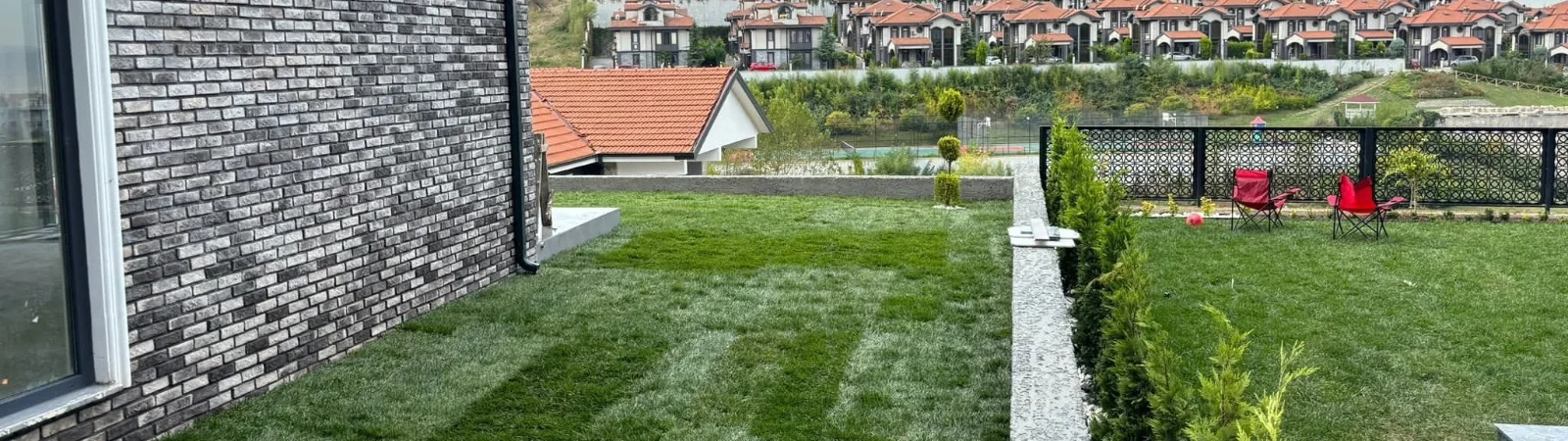 Serilmiş çim ve servi bordürüyle düzenlenmiş bahçe