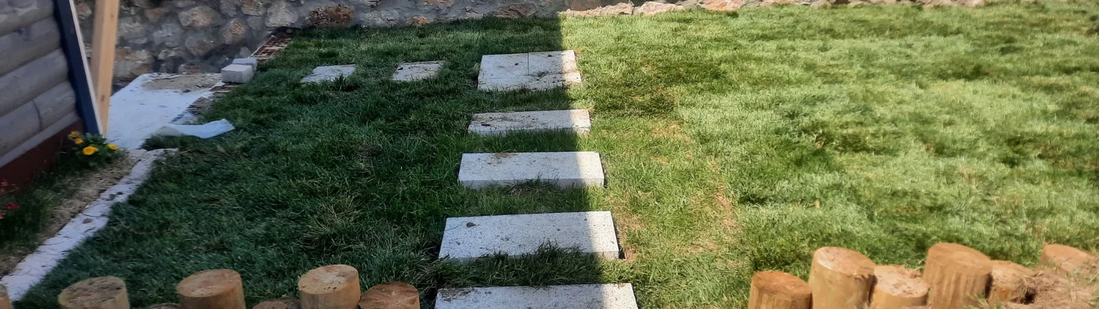Çimde granit basamak taşı yolu ve kenarında ahşap palisat bordür